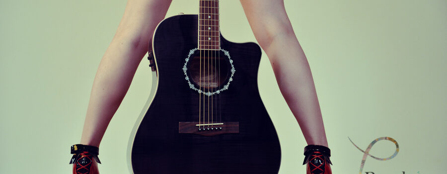 boudoir photo of guitar between a women's legs